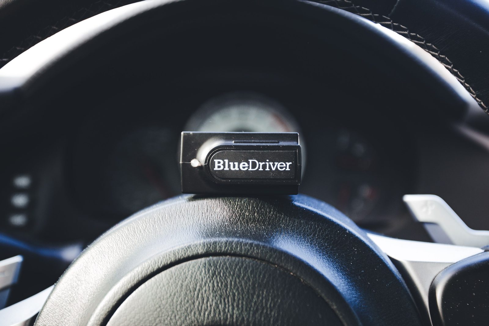 Lecteur OBD tenu en main devant le volant